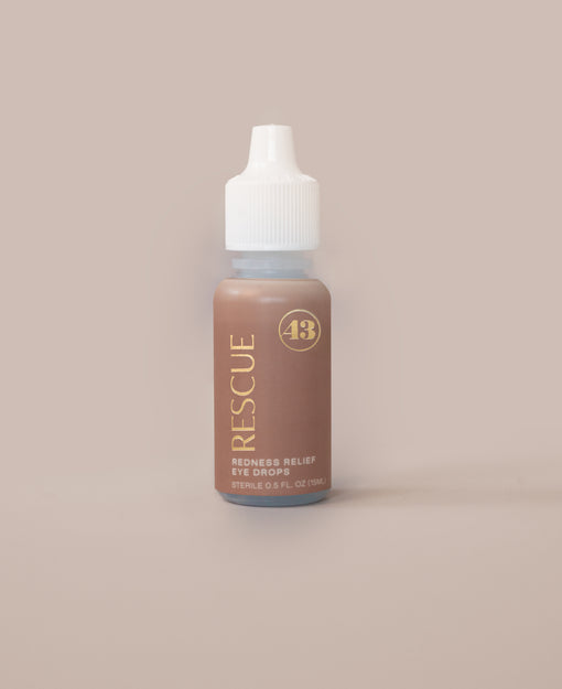 eye drop product bottle with tan label and gold text reading "rescue redness relief eye drops"
