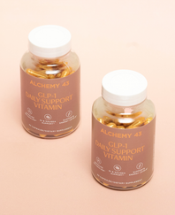 two GLP-1 vitamin bottles next to each other on a pinky-beige background. the bottles have tan labels and gold text reading "Alchemy 43 GLP-1 Daily Support Vitamin"