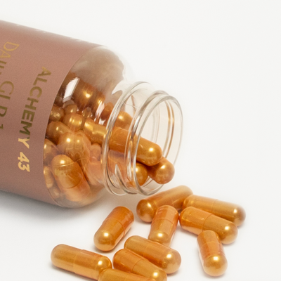 close up of GLP-1 vitamin bottle on its side with gold pill capsules spilling out